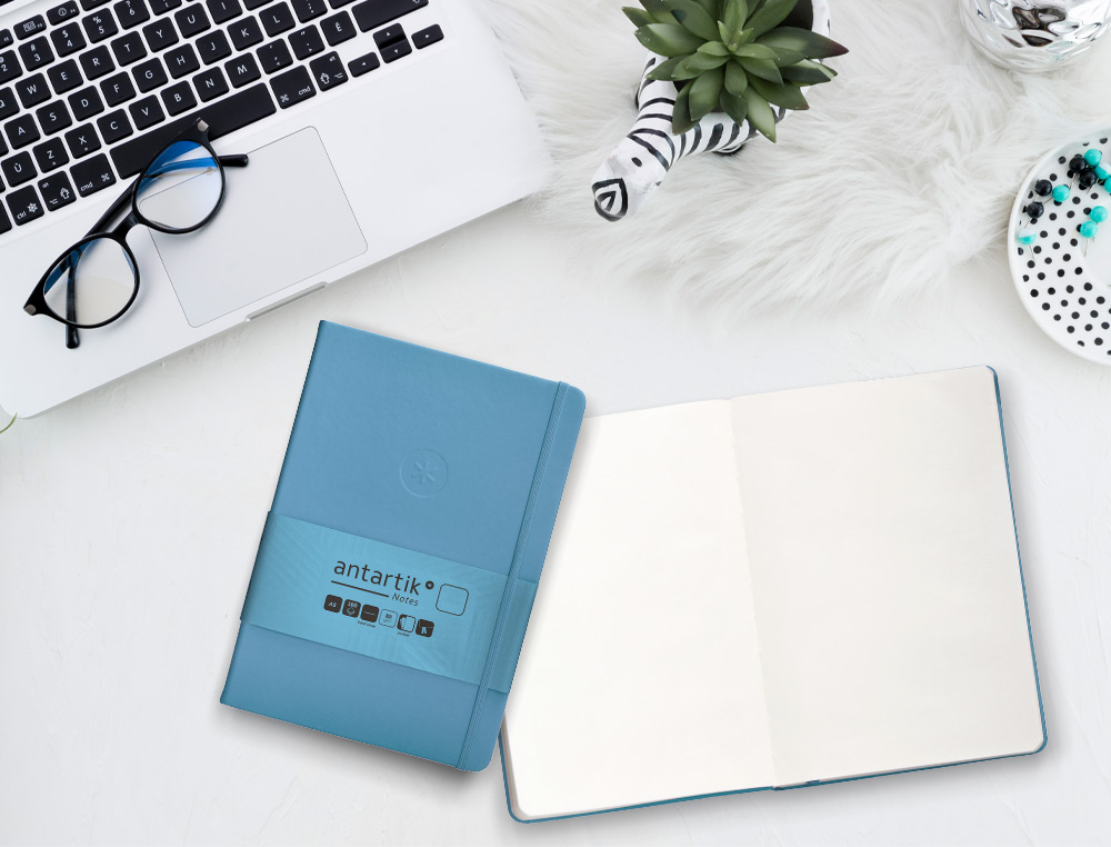 CUADERNO CON GOMILLA ANTARTIK NOTES TAPA DURA A5 HOJAS LISAS AZUL CLARO 100 HOJAS 80 GR FSC